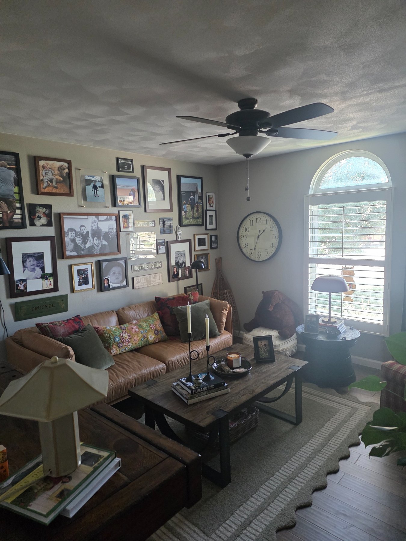Leather sofa beneath a wall of family photographs, with layered cushions and a wood coffee table.